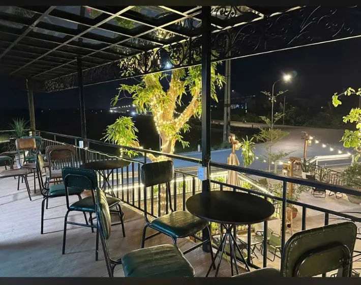 Khu vực ngồi tầng trên buổi tối với bàn ghế và cây đèn